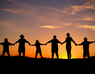 people holding hands on a hill with the sun behind them